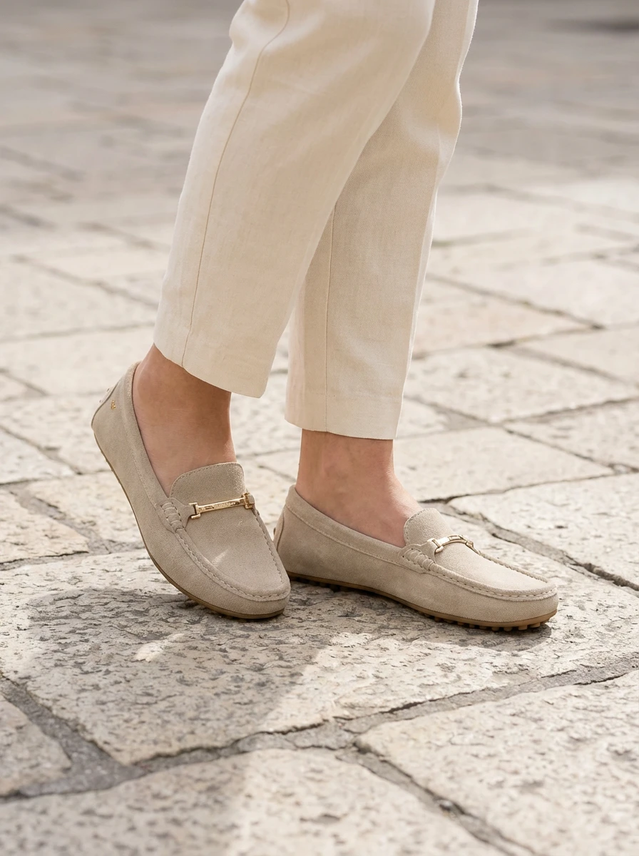 Kožené mokasíny na nohách ženy kráčajúcej po mestskej dlažbe na jar